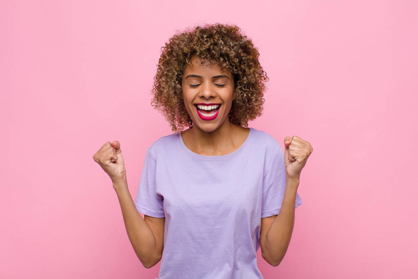 young african american woman looking extremely happy and surprised, celebrating success, shouting and jumping against pink wall - Fotografie, Obrázek