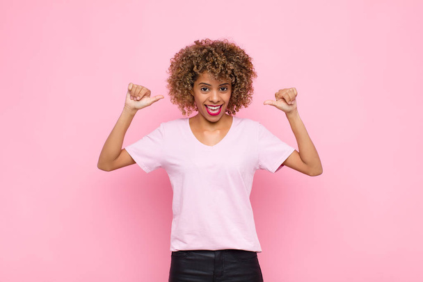young african american woman feeling proud, arrogant and confident, looking satisfied and successful, pointing to self against pink wall - Foto, Imagem