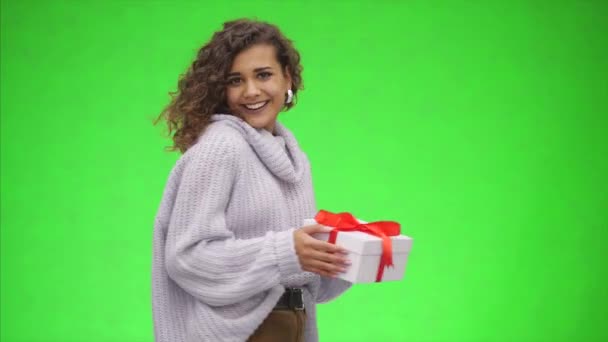 Afro-American woman is holding giftbox with red ribbon and is giving it to you. Best wishes. Close up. Copy space. - Imágenes, Vídeo