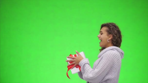 Afro-American woman is catching a giftbox with red ribbon and is giving it to you. Best wishes. Close up. Copy space. - Imágenes, Vídeo