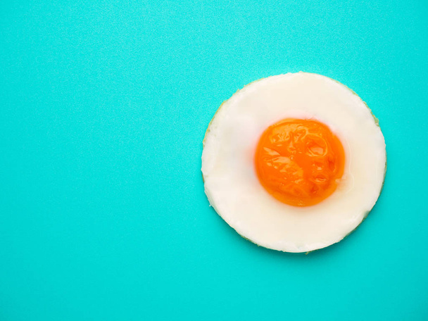 Perfect circle fried egg on blue-green background - Foto, Imagem