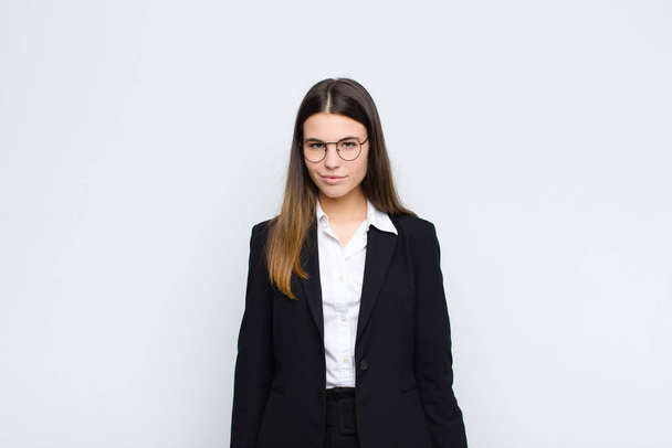 young businesswoman looking proud, confident, cool, cheeky and arrogant, smiling, feeling successful against white wall - Фото, зображення