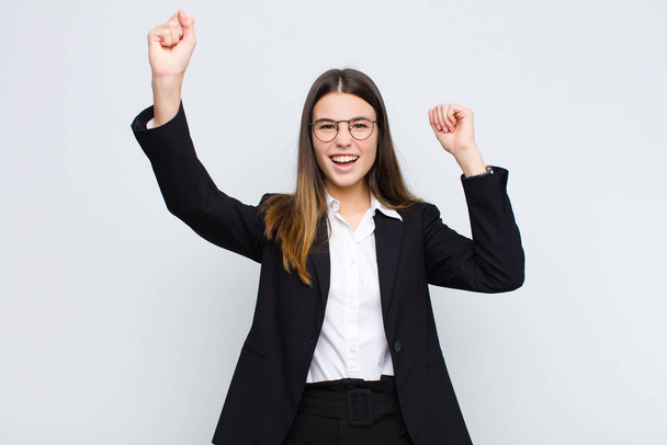молода бізнес-леді кричить тріумфально, виглядає як схвильований, щасливий і здивований переможець, святкуючи на білій стіні
 - Фото, зображення