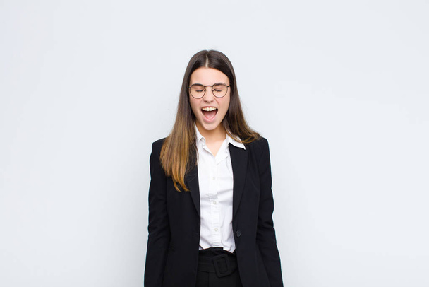 young businesswoman shouting aggressively, looking very angry, frustrated, outraged or annoyed, screaming no against white wall - Fotoğraf, Görsel