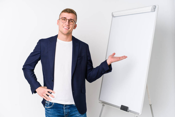 Young coaching man showing a white board showing a copy space on a palm and holding another hand on waist. - Photo, Image