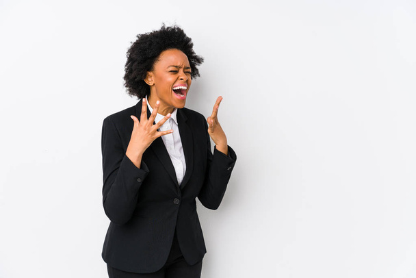 Африканская деловая женщина средних лет на белом фоне кричит громко, держит глаза открытыми и руки напряженными
. - Фото, изображение
