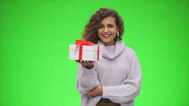 Afro-American woman is holding giftbox with red ribbon and is giving it to you. Best wishes. Close up. Copy space. - Felvétel, videó