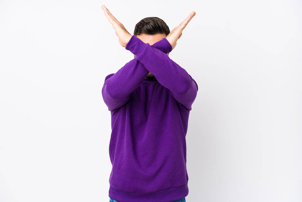 Young caucasian man against a white background isolated keeping two arms crossed, denial concept. - Photo, Image