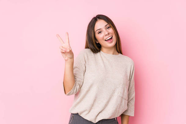 Young caucasian woman posing isolated joyful and carefree showing a peace symbol with fingers. - Photo, Image