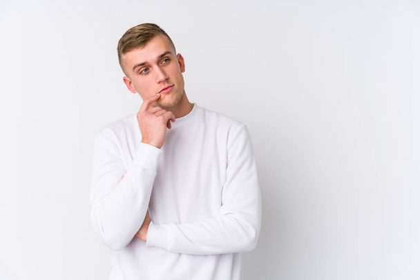 Young caucasian man on white background relaxed thinking about something looking at a copy space. - 写真・画像