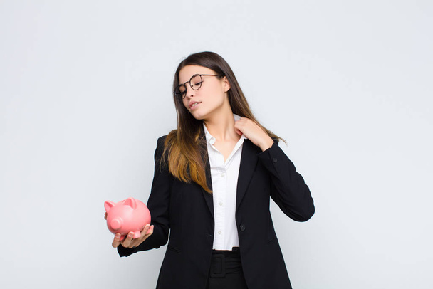 young pretty woman feeling stressed, anxious, tired and frustrated, pulling shirt neck, looking frustrated with problem with a piggy bank - Foto, Imagen