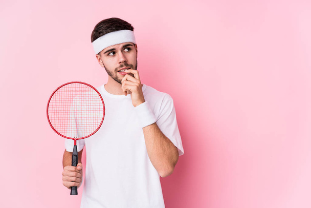 Jeune homme caucasien jouant au badminton isolé détendu penser à quelque chose en regardant un espace de copie
. - Photo, image