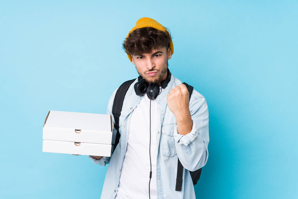 Νεαρός Άραβας φοιτητής που κρατά τις πίτσες απομονωμένες δείχνοντας γροθιά στην κάμερα, επιθετική έκφραση προσώπου. - Φωτογραφία, εικόνα