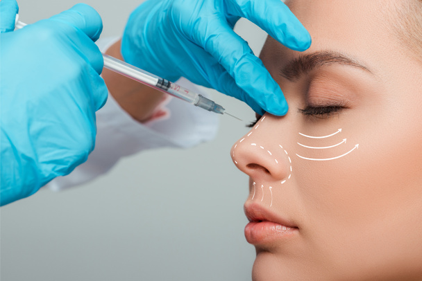 vue recadrée du cosmétologue faisant l'injection de beauté dans le nez à la femme attrayante isolée sur gris
 - Photo, image