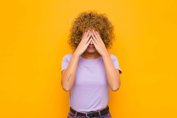 young afro woman looking stressed and frustrated, working under pressure with a headache and troubled with problems against orange wall - Foto, immagini