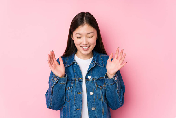 Mulher chinesa jovem posando em um fundo rosa isolado alegre rindo muito. Conceito de felicidade
. - Foto, Imagem