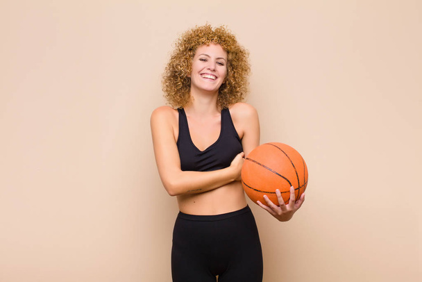 young afro woman laughing happily with arms crossed, with a relaxed, positive and satisfied pose sport concept - Фото, изображение