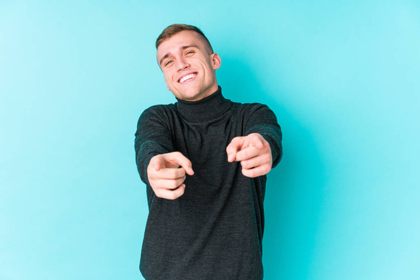 Young caucasian man on a blue background cheerful smiles pointing to front. - Photo, Image