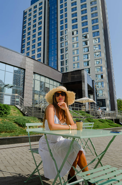 hermosa mujer bronceada delgada en un sombrero de paja y un sundre blanco
 - Foto, imagen