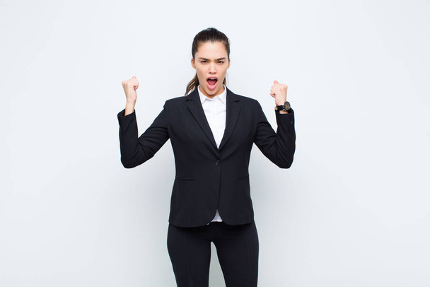 young pretty woman shouting aggressively with an angry expression or with fists clenched celebrating success business concept - Foto, imagen