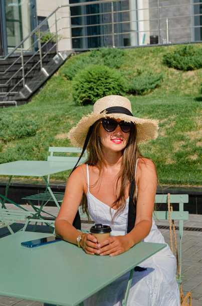 藁帽子の美しい細い日焼けした女性と白い日傘 - 写真・画像