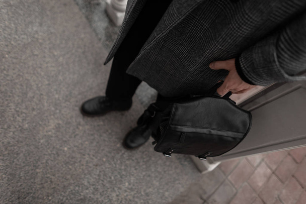 Roupas masculinas na moda e acessórios. Close-up. O homem elegante jovem em um casaco xadrez na moda em botas com uma mochila de couro na moda está de pé na rua. Nova colecção. Moda sazonal
. - Foto, Imagem