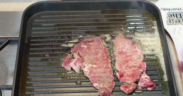 A woman puts thinly sliced steaks on a hot pan - Záběry, video