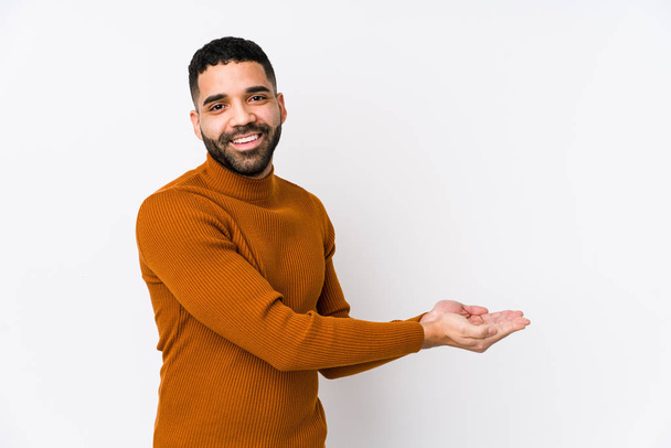 Young latin man against a white background isolated holding a copy space on a palm. - Photo, Image