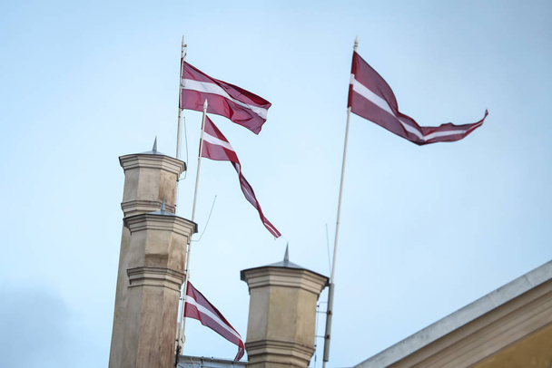 4 Latvia latvian flags waving on 4 flagpoles in wind. Clear blue - Photo, Image