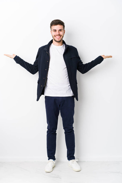 Full body young caucasian man isolated makes scale with arms, feels happy and confident. - Photo, Image
