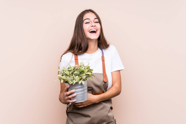Joven jardinero mujer caucásica sosteniendo una planta aisladariendo y divirtiéndose
. - Foto, imagen