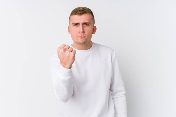 Young caucasian man on white background showing fist to camera, aggressive facial expression. - Photo, Image