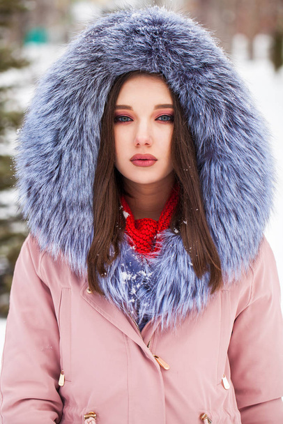 Young blonde woman in blue down jacket in winter street - Foto, Imagem
