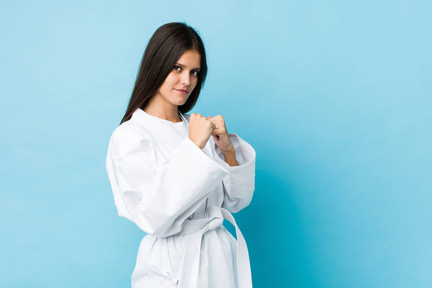 Nuori valkoihoinen nainen harjoittelee karatea eristettynä sinisellä pohjalla - Valokuva, kuva