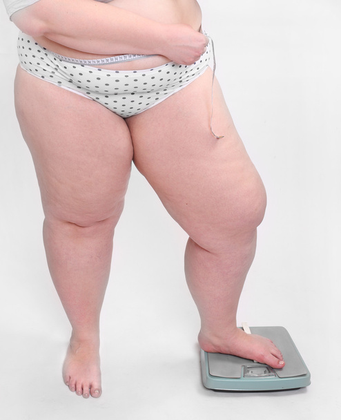 felice donna in sovrappeso misurare la sua pancia vita da metro bastone su una macchina di pesatura
. - Foto, immagini