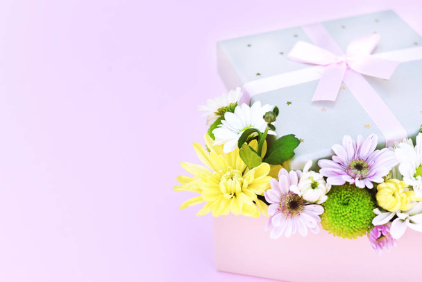 Χαριτωμένη σύνθεση πολύχρωμα λουλούδια σε ένα κουτί σε ένα ροζ φόντο. Πανό διακοπών. Υπάρχει χώρος για κείμενο.. - Φωτογραφία, εικόνα