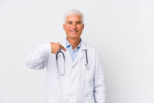 Mature caucasian doctor man person pointing by hand to a shirt copy space, proud and confident - 写真・画像