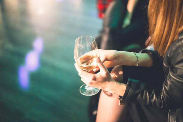 Una copa de vino en las manos de una joven vestida de cuero
 - Foto, Imagen