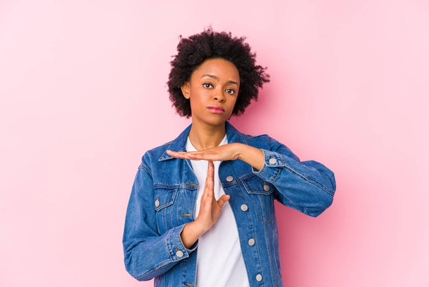 Joven mujer afroamericana contra un fondo rosa aislado mostrando un gesto de tiempo de espera
. - Foto, imagen