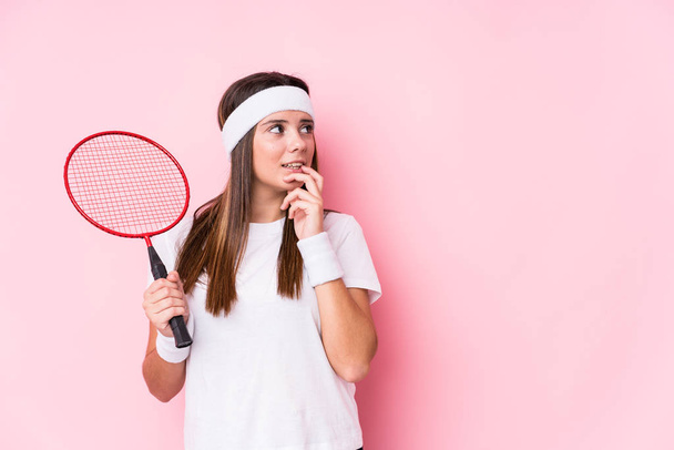 Junge kaukasische Frau spielt Badminton und denkt entspannt über etwas nach, das einem Kopierraum ähnelt. - Foto, Bild