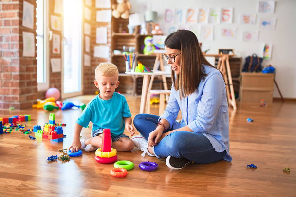 Young caucasian child playing at playschool with teacher. Mother and son at playroom with intelligence toy - Foto, Imagem
