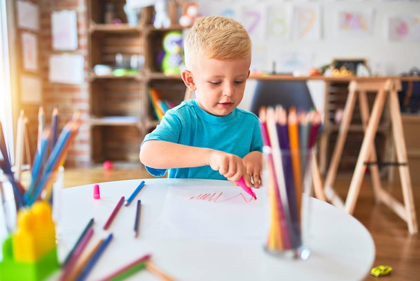 幼稚園で色鉛筆で遊んでいる若い白人の子供。未成年の男の子幸せ- playroom. - 写真・画像