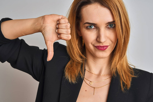 Close up of caucasian elegant business woman over isolated background with angry face, negative sign showing dislike with thumbs down, rejection concept - 写真・画像