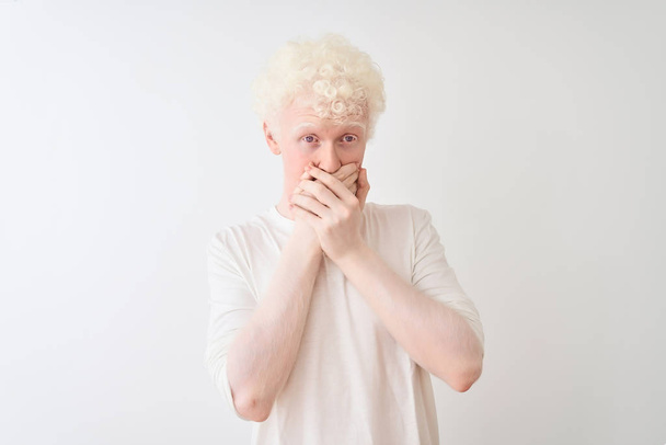 Nuori albiino vaalea mies päällään rento t-paita seisoo yli eristetty valkoinen tausta järkyttynyt peittää suu kädet erehdyksen. Salainen käsite
. - Valokuva, kuva
