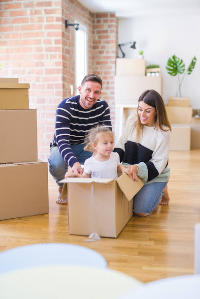 Belle famille, enfant jouant avec ses parents chevauchant boîte de fanny en carton à la nouvelle maison
 - Photo, image