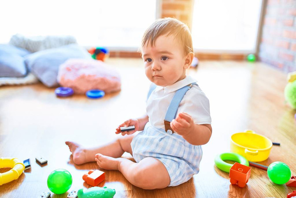 Adorable niño jugando alrededor de un montón de juguetes en el jardín de infantes
 - Foto, Imagen