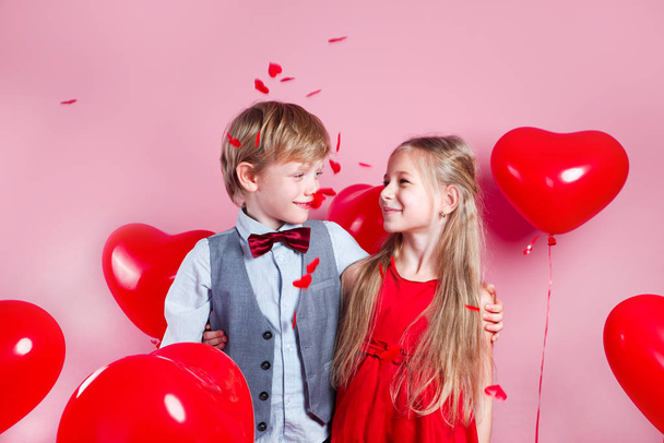 Leuke jongen en meisje die elkaar aankijken op een achtergrond van harten. Valentijnsdag. - Foto, afbeelding