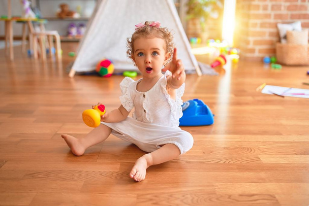 Beautiful caucasian infant playing with toys at colorful playroom. Happy and playful at kindergarten. - Photo, Image
