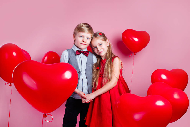 Happy kids with red heart balloons on a pink background - Foto, imagen