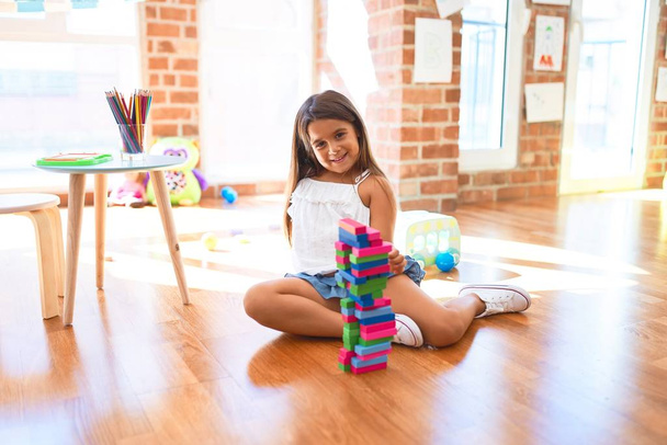Adorable tout-petit assis sur le sol. Jouer avec des blocs de construction en bois à la maternelle
 - Photo, image